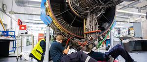 Kurzarbeit. Drei Männer arbeiten in einer Werkstatt von Lufthansa Technik am Triebwerk eines Flugzeuges. 