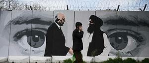 Straßenszene in Kabul: Ein Passant vor einem Wandbild mit den Unterhändlern für das USA-Abkommen mit den Taliban. 