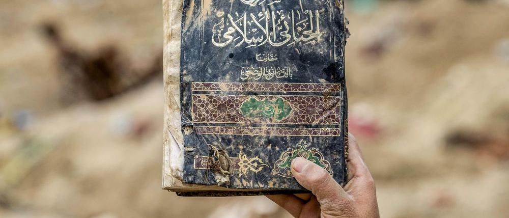 Ein Anti-IS-Kämpfer präsentiert ein Gesetzbuch aus der Zeit des „Kalifats“, das in Ostsyrien gefunden wurde.