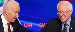 Biden und Sanders geben sich bei einer Debatte den Ellbogen.
