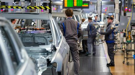 Auf Abstand: Mitarbeiter bauen im Karosseriebau im VW Werk Türen, Kotflügel und Motorhauben an Volkswagen an.