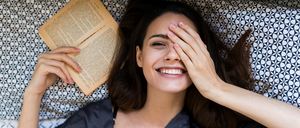 Auf ins Buchabenteuer. Eine Frau liest im Bett.