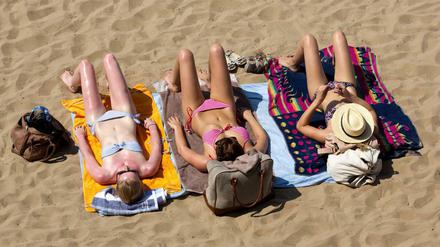 Bei hochsommerlichen Temperaturen bräunen sich weibliche Besucher in der Mittagssonne im Strandbad Wannsee.