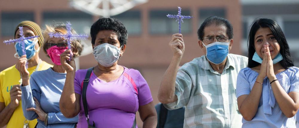 Menschen mit Mundschutzmasken in Caracas beten und halten Kreuze hoch, als der «Nazareno de San Pablo», eine Jesus-Statue, während der Feierlichkeiten zur Karwoche in einem Mobil durch die Stadt geführt wird. 