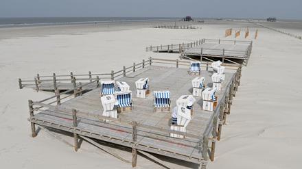 Ungenutzte Strandkörbe stehen auf einer Holzterrasse am Strand von St. Peter Ording.
