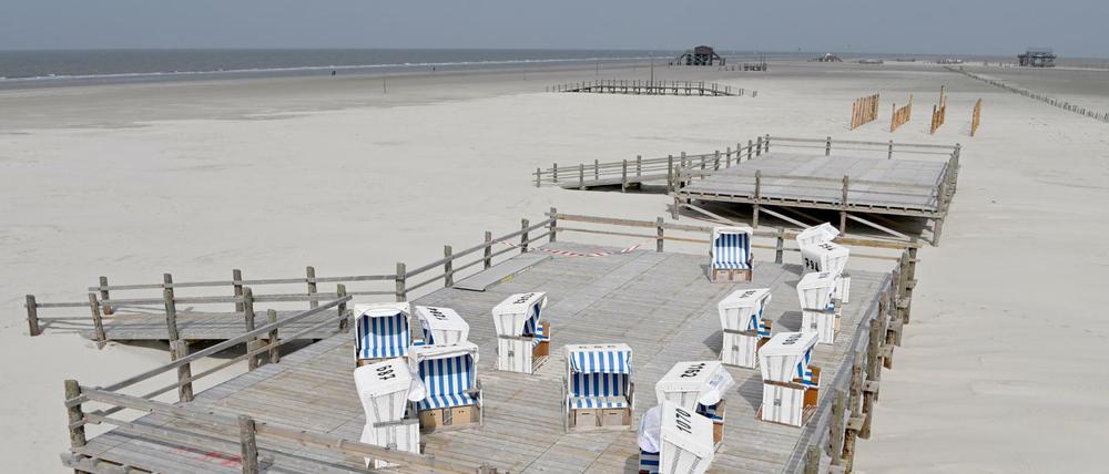 Ungenutzte Strandkörbe stehen auf einer Holzterrasse am Strand von St. Peter Ording.