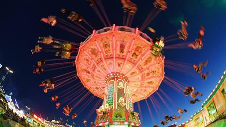 Besucher fahren auf dem Oktoberfest abends mit einem Kettenkarussell. 