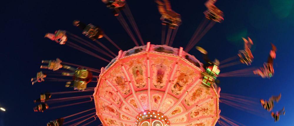 Besucher fahren auf dem Oktoberfest abends mit einem Kettenkarussell.