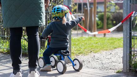 Ein Kind steht vor einem abgesperrten Spielplatz.