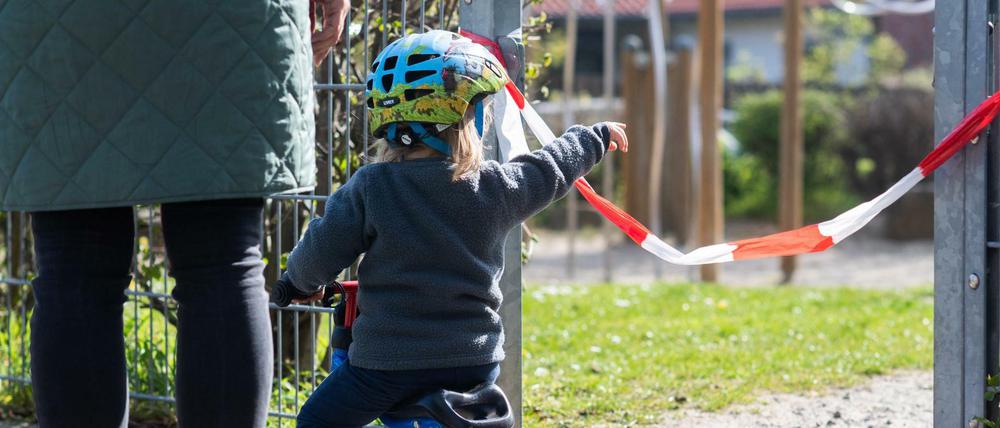 Ein Kind steht vor einem abgesperrten Spielplatz.