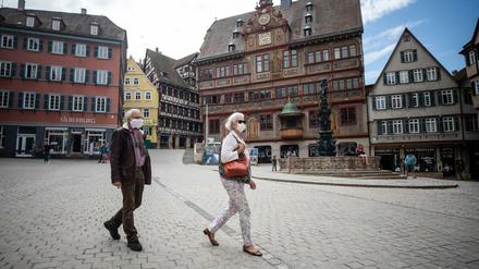 Ein älteres Paar läuft mit Schutzmasken am Tübinger Rathaus vorbei. Auch die Stadt Tübingen plant eine Maskenpflicht.
