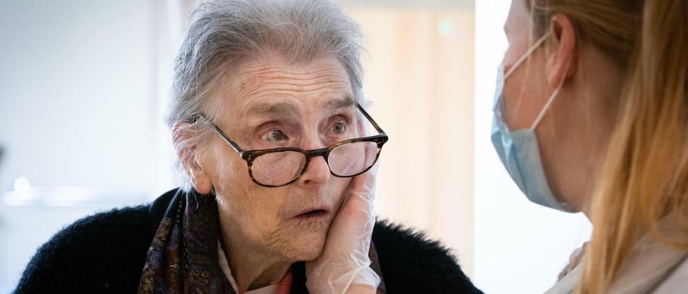 Eine Krankenschwester hält mit einer Hand das Gesicht einer Bewohnerin des Pflegeheims "La Retraite Fleurie" in Belgien.