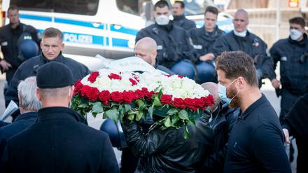 Vorn ein Blumengebinde, hinten die Polizei: Eine Beerdigung im Kreise der Familie Remmo unter Corona-Bedingungen.