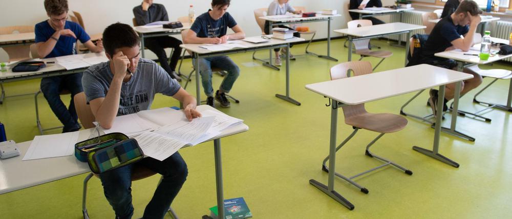 Schüler sitzen beim schriftlichen Abitur an Einzeltischen, einige Tische sind freigeblieben.