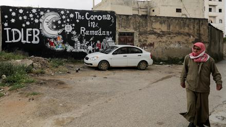 Ein Mann läuft in der syrischen Stadt Binnish an einem Graffiti vorbei.