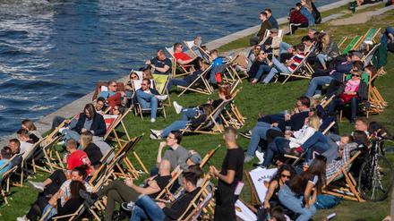 Zahlreiche Menschen genießen auf den Liegestühlen den sonnigen Nachmittag am Spreeufer, trotz Corona-Sperre.