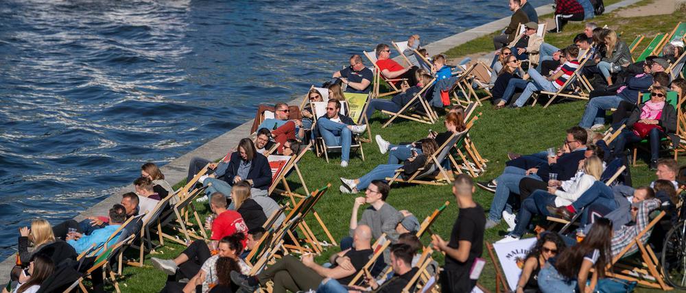 Zahlreiche Menschen genießen auf den Liegestühlen den sonnigen Nachmittag am Spreeufer, trotz Corona-Sperre.