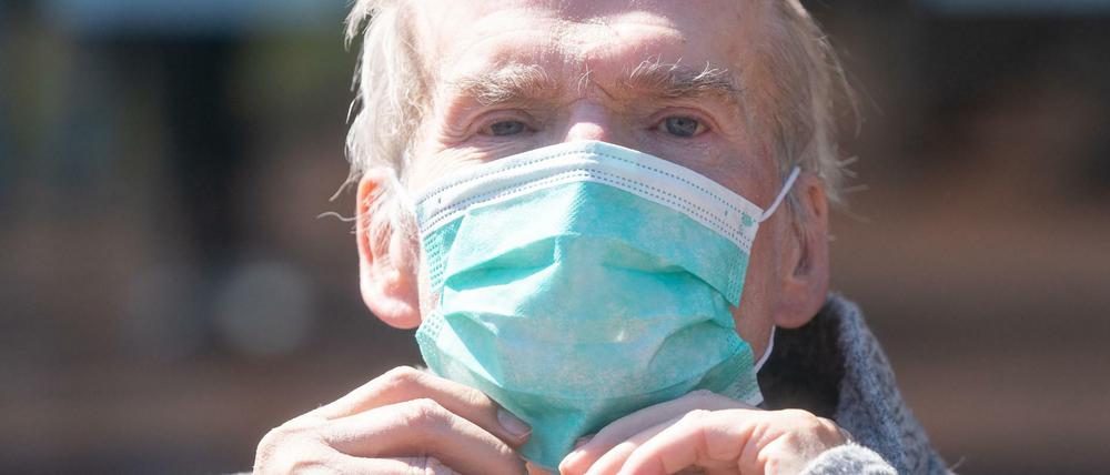 Ein Heimbewohner eines Seniorenheims in Dresden sitzt mit Mundschutz im Freien.