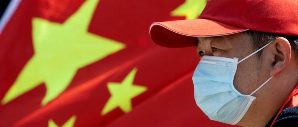 In Wuhan nimmt ein Freiwilliger mit Mundschutz an einer Abschiedszeremonie für Mediziner teil, die der Stadt nach dem Ausbruch des Virus halfen.