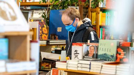 Auf der Suche nach Corona-Literatur? Ein Kunde steht mit Mundschutz in einem Buchladen in Regensburg 