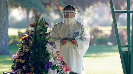 Das Virus verändert die Trauer. Ein Priester mit Gesichtsschutz bei der Beerdigung eines Corona-Patienten. Foto: