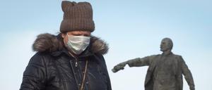Frau in St. Petersburg vor einer Statue von Lenin, dem Begründer der Sowjetunion