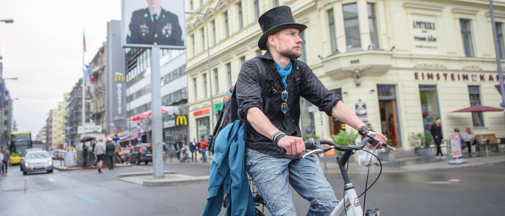 Juha Järvinen, Teilnehmer des Experiments Grundeinkommen in Finnland, fährt auf einem geliehenen Fahrrad am Checkpoint Charlie vorbei.