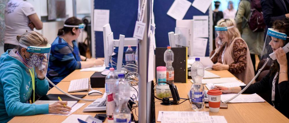 Mitarbeiter des Gesundheitsamtes Mitte mit Gesichtsschutzschirm telefonieren im Lagezentrum des Gesundheitsamt Mitte.