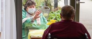 Ilona Spottke (l) und Karl Gegner unterhalten sich durch eine Fensterscheibe im Erdgeschoss eines Pflegeheims.