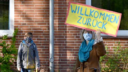 Eine Lehrerin begrüßt Schüler in einer Grundschule.