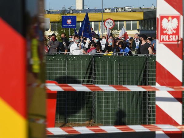 Menschen stehen auf polnischer Seite hinter der geschlossenen Grenze und protestieren - unter anderem mit einer Europafahne.