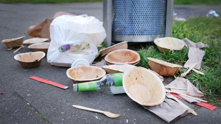 Einweggeschirr neben einem vollen Mülleimer an einem Park. Wegen der Corona-Krise nimmt das Abfallaufkommen zu (Symbolbild).