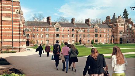 Studierende gehen auf dem Campus des Keble College in Richtung des historischen Hauptgebäudes.