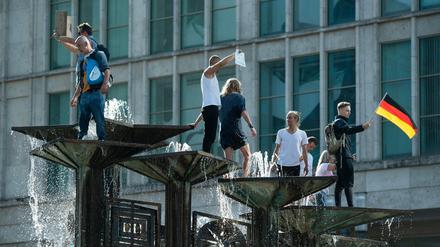 Menschen sind bei einer Demonstration auf dem Alexanderplatz auf den Springbrunnen "Brunnen der Völkerfreundschaft" geklettert.
