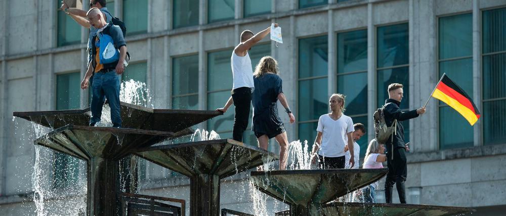 Menschen sind bei einer Demonstration auf dem Alexanderplatz auf den Springbrunnen "Brunnen der Völkerfreundschaft" geklettert.