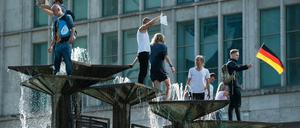 Menschen sind bei einer Demonstration auf dem Alexanderplatz auf den Springbrunnen "Brunnen der Völkerfreundschaft" geklettert.