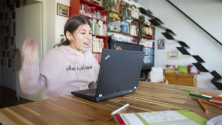 Eine Schülerin sitzt zu Hause vor ihrem Laptop und flippt aus.