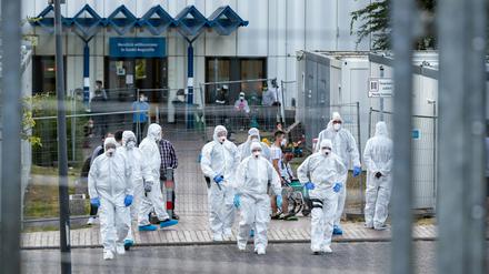 Beamte der Polizei und des Ordnungsamtes in Schutzanzügen sowie Bewohner in einer Flüchtlingsunterkunft in St. Augustin (Rhein-Sieg-Kreis).