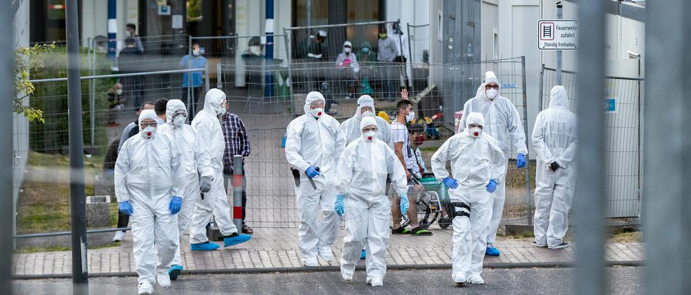 Beamte der Polizei und des Ordnungsamtes in Schutzanzügen sowie Bewohner in einer Flüchtlingsunterkunft in St. Augustin (Rhein-Sieg-Kreis). 