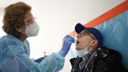 Eine Schwester nimmt bei einem Patienten einen Corona-Abstrich vor.
