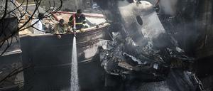 Feuerwehrmänner löschen Wrackteile der Maschine.