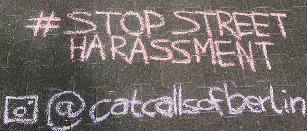 Kreideschriftzug auf der Straße, der sexuelle Belästigung beschreibt ("auf den Arsch geschlagen").