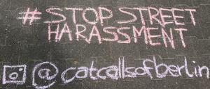 Kreideschriftzug auf der Straße, der sexuelle Belästigung beschreibt ("auf den Arsch geschlagen").