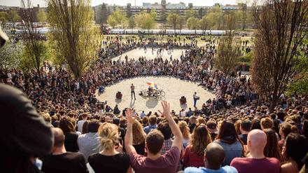 Berliner und Touristen sitzen bei Sonne im Mauerpark in Berlin und verfolgen das wöchentliche Karaokesingen.