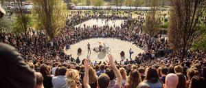Berliner und Touristen sitzen bei Sonne im Mauerpark in Berlin und verfolgen das wöchentliche Karaokesingen. 