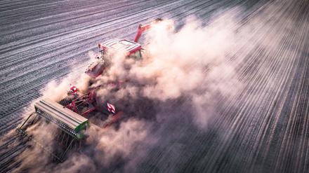 Ein Traktor verschwindet bei der Aussaat von Winterraps in einer Staubwolke.