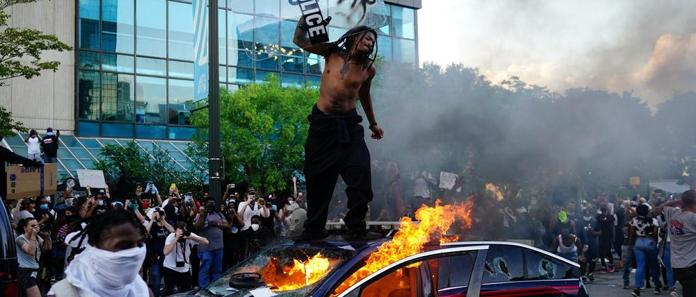 Ein Demonstrant steht auf einem brennenden Polizeiauto in Atlanta. =