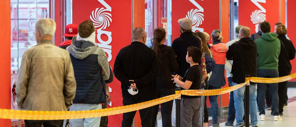 Kunden stehen in Dresden vor einem Elektronikmarkt an, weil immer nur eine bestimmmte Anzahl Kunden den Laden betreten darf.