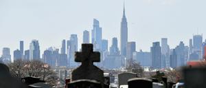 Grabsteine auf dem Linden Hill Methodist Cemetery mit der Skyline von Manhattan im Hintergrund.