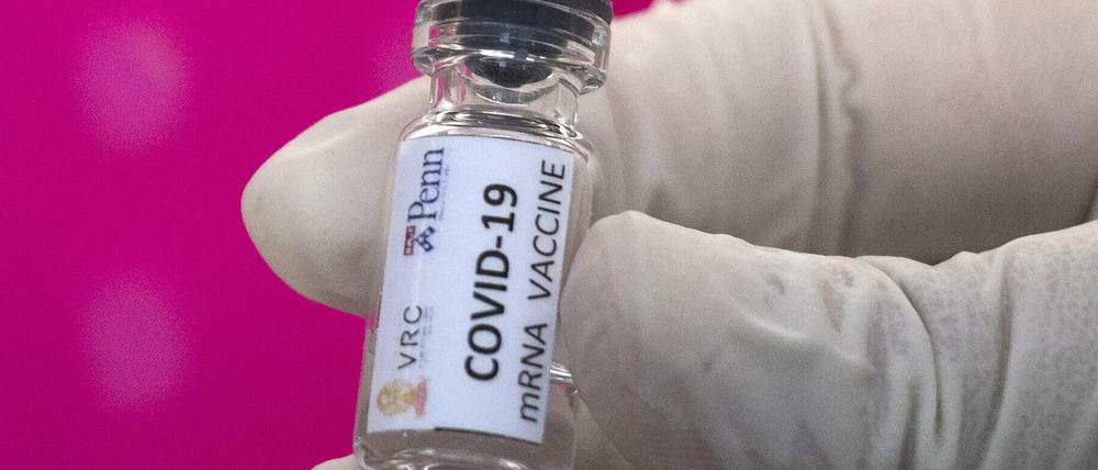 Ein Labortechniker hält einen Glasbehälter eines sich in der Entwicklung befindlichen, möglichen Covid-19-Impfstoffs in der Hand.